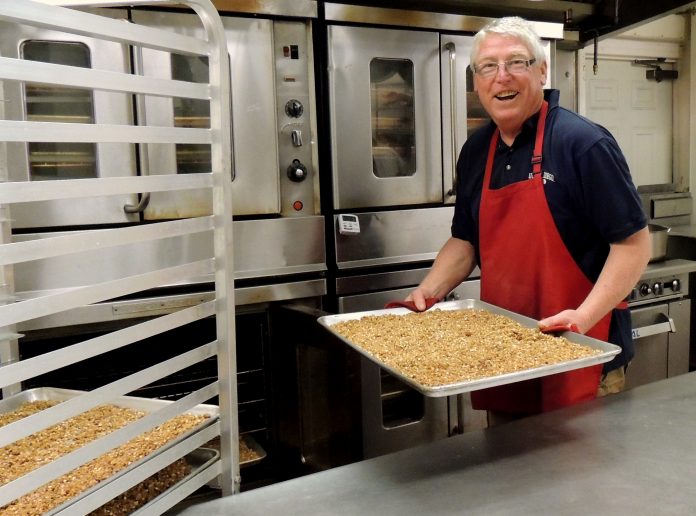 Curtis Moore, owner of Safari Crunch, removes a pan of Cherry Cheetah granola from the oven..jpg